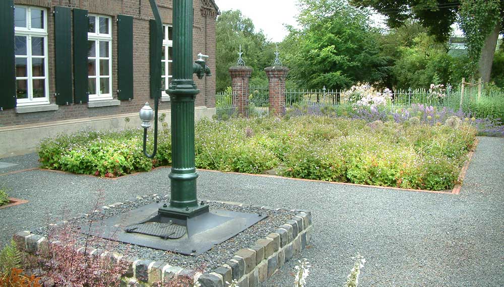 Ongebruikt Boerderij tuin met oude waterpomp en plantvakken met buxushaagjes. RO-05